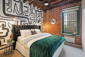 The king bed in the first bedroom is backed against an abstract mural. A ceiling fan helps to keep you cool year round.