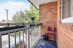 The breezy balcony features unique floor tiling and is decorated with plants, plus a chair.