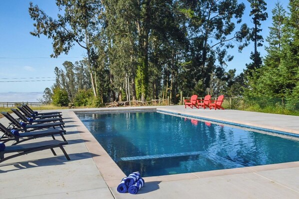 Poolside paradise with cozy sun loungers and an in-pool hot tub. 