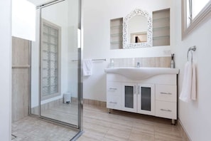 Adjoining bathroom featuring a basin and walk-in shower