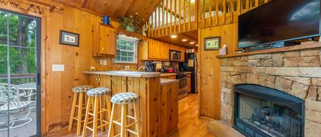 This cozy cabin features one bedroom and a loft, along with a fireplace and TV with a cable box for entertainment. It offers a full kitchen with a breakfast nook and counter island, and a balcony for fresh air and scenic views.