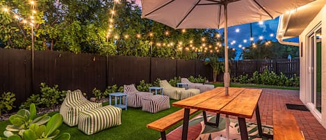 Sun lounger beanbags and picnic table in the backyard under bistro lights