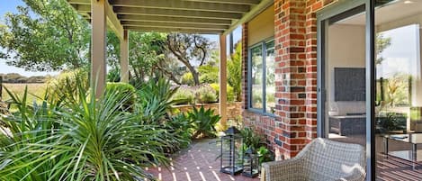 Seating on the outdoor patio area overlooks the surrounding paddocks, with views of the ocean
