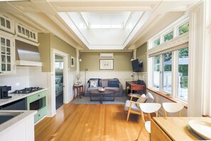 A living nook is furnished with a plush two-person couch, additional armchair and sits next to a wall-mounted, flat-screen TV with Chromecast.