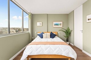 The spacious bedroom highlights a queen-sized bed with side tables and reading lights and walk-in wardrobe.

