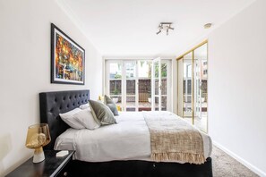 The spacious primary bedroom features a queen-size bed, mirrored built-ins and a cosy armchair, as well as direct access to the courtyard.