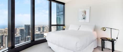 The spacious master bedroom features a queen-size bed and floor-to-ceiling windows offering stunning views of the city.
