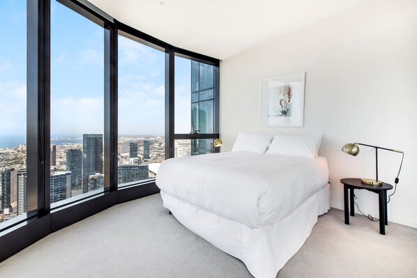 The spacious master bedroom features a queen-size bed and floor-to-ceiling windows offering stunning views of the city.
