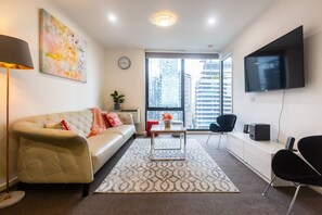 The living room is light and bright, with a retro leather lounge and wall-hung TV.