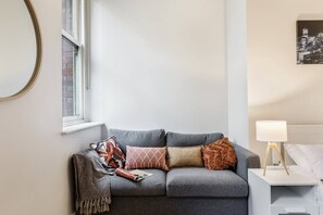 A cosy sofa nestled alongside the window offers an ideal spot to enjoy your morning coffee or settle in with a movie. 
