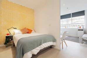 A bedroom features a plush double bed dressed in high-quality linen and convenient built-in mirrored wardrobes