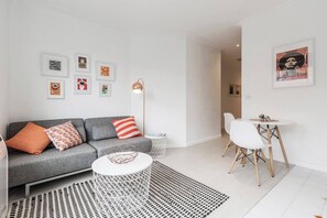 A well-lit living area features a chic grey couch, coffee table, beautiful copper lamp and a TV for cosy nights in