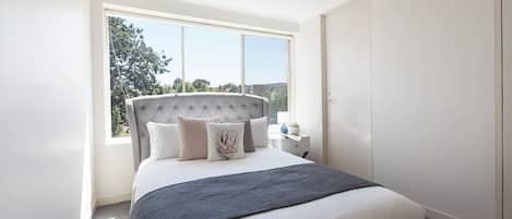The beautiful, sunlit bedroom has a luxury queen-size bed, fan, huge built-in wardrobe and access to an ensuite bathroom