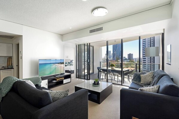 A spacious and bright living room with smart TV opens up to the beautiful alfresco balcony with ocean views.