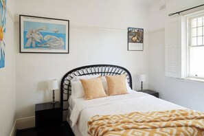 The light and airy first bedroom includes a queen-size bed and a ceiling fan.

