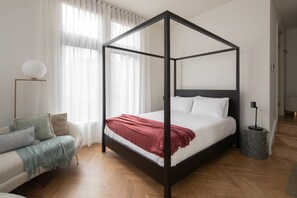 A modern, four-poster queen bed, complete with side tables and reading lamps, provides a comfortable night’s sleep. 
