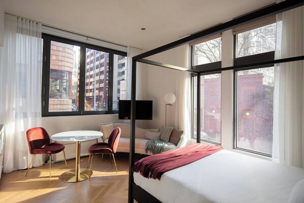 Unwind in the cosy couples corner adorned with a queen-size bed, a stylish dining area, a plush couch, all accented with a touch of passionate red.