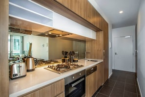 The modern kitchen and hidden laundry is complete with stainless steel appliances, toaster, hot water kettle and all the basics