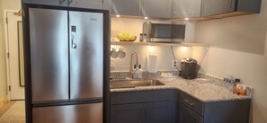 Kitchen has a refrigerator, microwave, coffee maker, silverware & various dishes