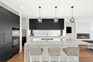 The kitchen is a masterpiece of design, featuring sleek monochrome cabinetry, luxe Essastone Calacatta benchtops