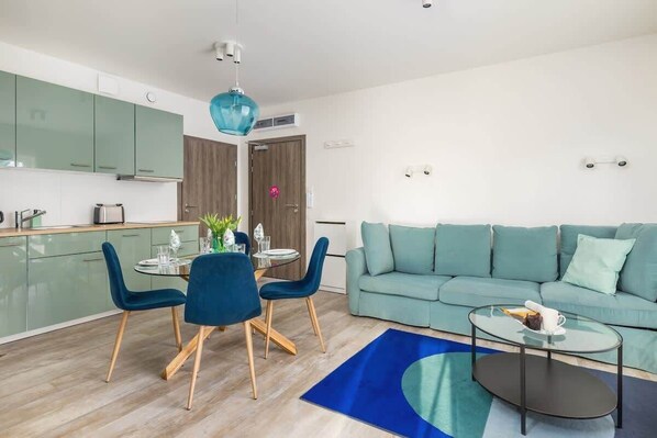 A bright living room with a mint green sofa, blue coffee table, and modern decor.

