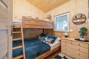 A children’s bedroom featuring a wooden bunk bed, colorful bedding, and practical storage options, perfect for a family retreat.
