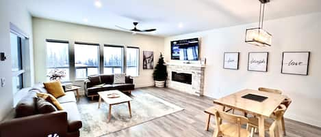 Open living room with electric fireplace and large smart TV with cable