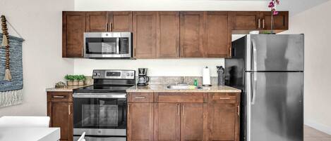 Everything you need in the kitchen: a functional full fridge, microwave, stove, and a range of utensils.