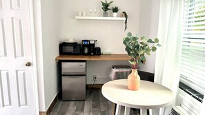 Kitchenette with coffee maker, microwave, toaster, mini fridge, coffee cup, wine glasses and silverwares.