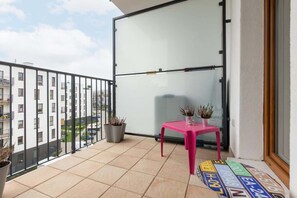 A small balcony with chairs, a table, and a view of the surrounding area, creating an inviting outdoor space.
