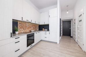 A modern kitchen featuring white cabinets, a brick backsplash, and built-in appliances for a stylish and functional design.
