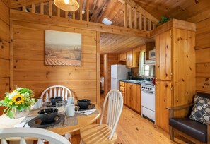 Cabin with dining table for four and kitchen.