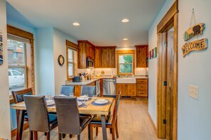 A view of the dining room accompanied by a view of the kitchen and entrance to the bathroom.