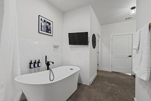 Luxurious Bathroom: a bathroom with a bathtub and a television on the wall.