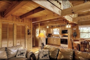 Cozy pet-friendly cabin in Sevierville, TN, featuring warm wood interiors, a fully equipped kitchen, and a rustic dining area. Unwind in the inviting living space with leather seating and nature-inspired décor. A romantic Sevierville cabin rental, near Pigeon Forge, with mountain views.