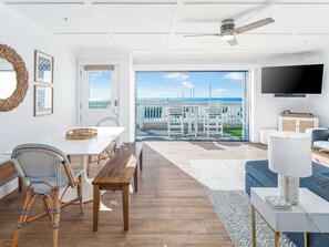 Spacious living space with contemporary furniture, a smart tv, and a dining area overlooking the ocean.