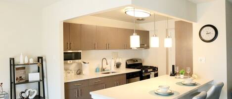 Spacious kitchen equipped with pots, pans, keurig, silverware, dishware, etc.