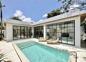 A beautiful tropical pool area with a garden and two day beds