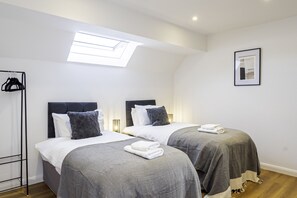 Cozy bedroom with two single beds, soft linens, and plenty of natural light—ideal for a comfortable and restful stay.