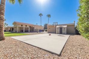 Spacious Entertainer's Backyard featuring a sparkling blue pool, hot tub, built-in BBQ, fire pit, lanai gazebo, putting green, half-court basketball, outdoor dining, and a large grass area perfect for yards games and furry friends.