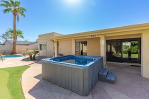 Spacious Entertainer's Backyard featuring a sparkling blue pool, hot tub, built-in BBQ, fire pit, lanai gazebo, putting green, half-court basketball, outdoor dining, and a large grass area perfect for yards games and furry friends.