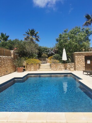 Private sunny pool with garden views that has comfortable seating area