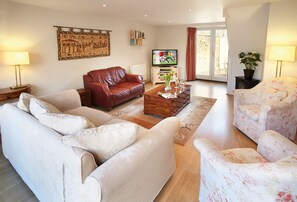 Dual aspect sitting room with sumptuous seating and french doors leading to the courtyard