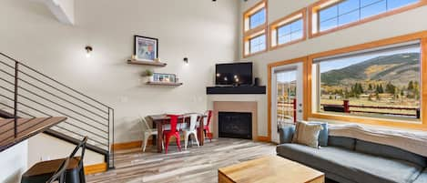 Living room with mountain views, private balcony, gas fireplace, and vaulted ceilings.