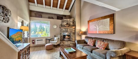 Beautiful hardwood floors, a stone fireplace, and vaulted ceiling in living room