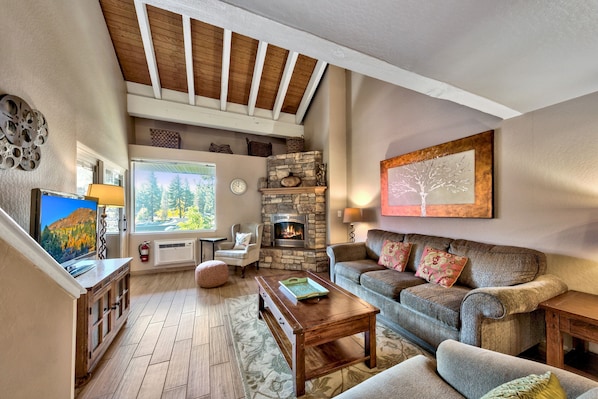 Beautiful hardwood floors, a stone fireplace, and vaulted ceiling in living room