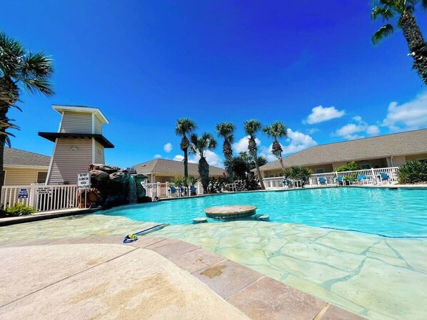 Pool area with scenic views, a waterfall feature, and seating with a table and stools.