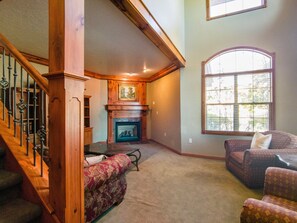 View from the front door entrance.  Livingroom with cozy fireplace, large windows to invite the outdoors in, and a flat screen TV for your viewing pleasure.