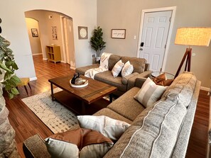 Large living room with sofa and love seat, Roku Smart TV, and ambient lighting.