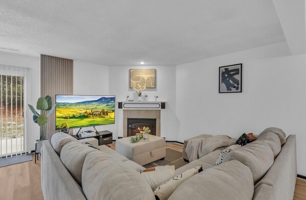 Living room with 65 inch smart Tv and comfortable sofa, and a  fire place